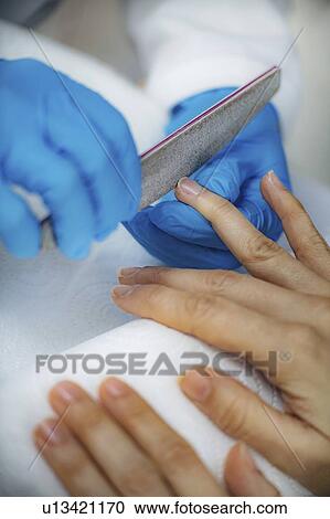 Stock Image - Filing fingernails at nail salon. Fotosearch