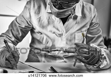 Stock Photograph - Forensic investigator examining evidence in lab. Fotosearch