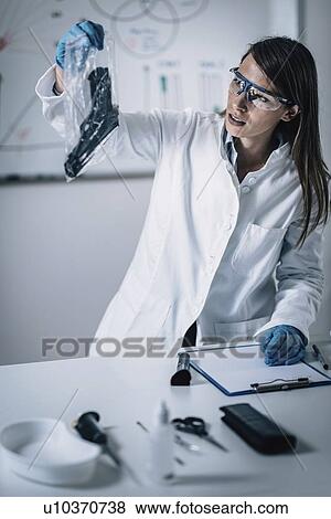 Stock Photo - Forensics expert examining crime scene evidence. Fotosearch