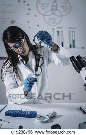 Stock Photograph - Forensics expert examining crime scene evidence. Fotosearch