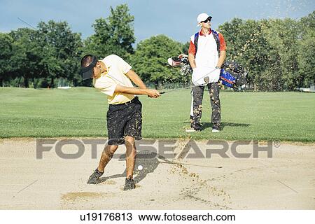Stock Image - Golfer playing from bunker. Fotosearch