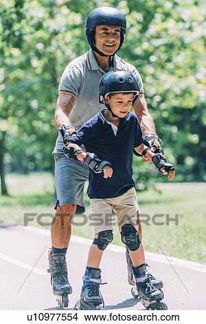 Picture - Grandfather teaching grandson to roller skate. Fotosearch