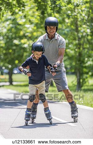 Stock Image - Grandfather teaching grandson to roller skate. Fotosearch
