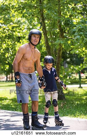 Stock Image - Grandfather teaching grandson to roller skate. Fotosearch