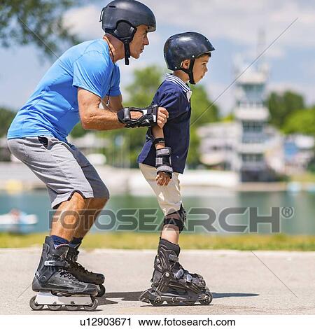 Stock Image - Grandfather teaching grandson to roller skate. Fotosearch