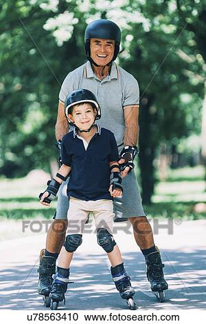Stock Image - Grandfather teaching grandson to roller skate. Fotosearch
