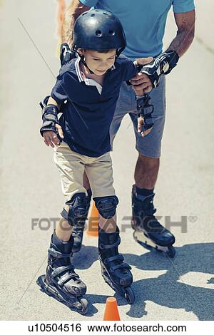 Stock Photograph - Grandfather teaching grandson to roller skate. Fotosearch