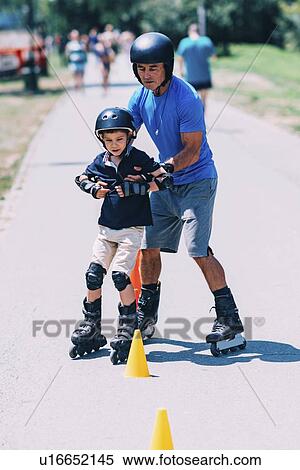 Stock Photography - Grandfather teaching grandson to roller skate. Fotosearch