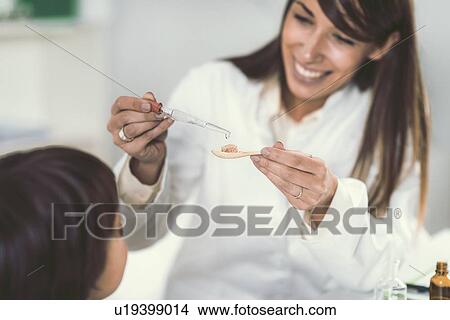 Picture - Homeopath giving remedy to child. Fotosearch