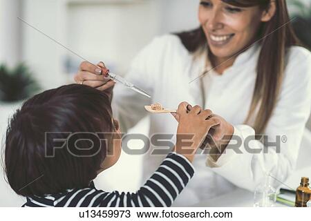Stock Image - Homeopath giving remedy to child. Fotosearch