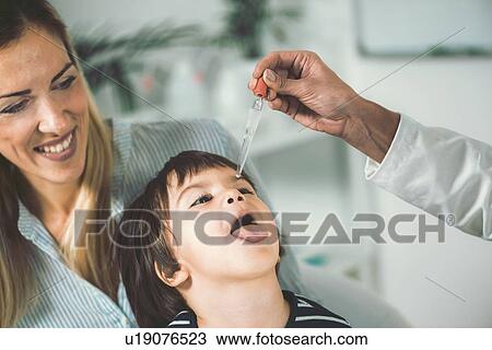 Stock Image - Homeopath giving remedy to child. Fotosearch