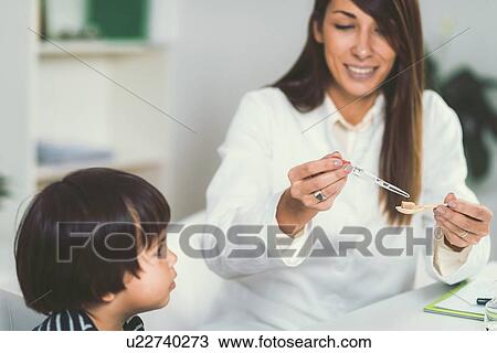 Stock Image - Homeopath giving remedy to child. Fotosearch