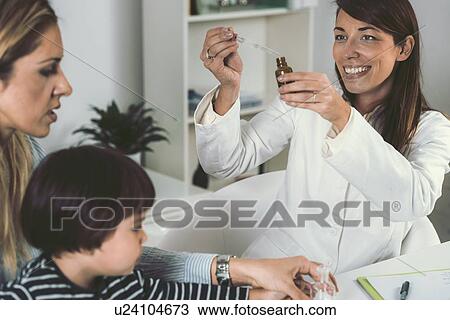 Stock Image - Homeopath giving remedy to child. Fotosearch