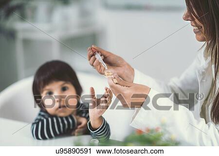 Stock Image - Homeopath giving remedy to child. Fotosearch
