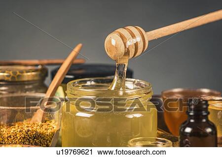 Stock Image - Honey flowing into a glass jar. Fotosearch