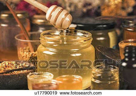 Stock Photo - Honey flowing into a glass jar. Fotosearch
