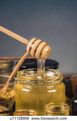 Stock Photograph - Honey flowing into a glass jar. Fotosearch