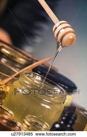 Stock Photography - Honey flowing into a glass jar. Fotosearch