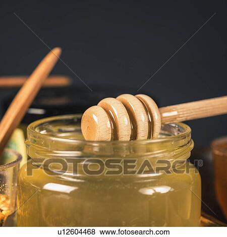 Stock Photo - Honey glass jar with wooden dipper. Fotosearch