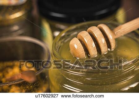 Stock Photo - Honey glass jar with wooden dipper. Fotosearch