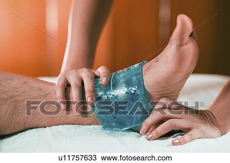 Stock Image - Ice pack on painful ankle. Fotosearch