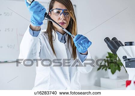 Stock Image - Laboratory technician with micropipette. Fotosearch