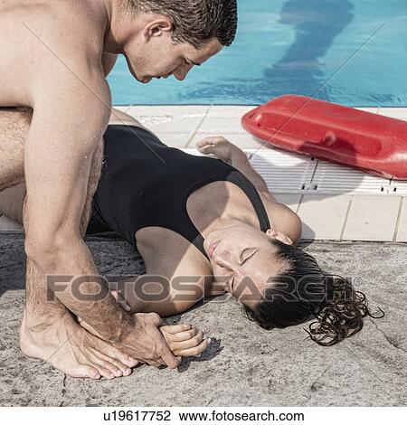 Stock Image - Lifeguard checking woman's pulse. Fotosearch
