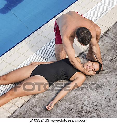 Stock Image - Lifeguard placing woman in recovery position. Fotosearch