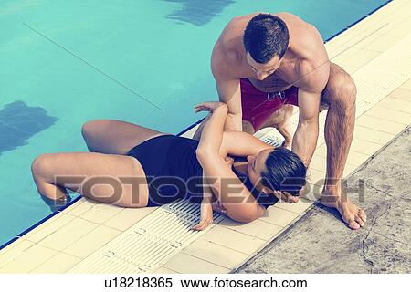 Stock Photography - Lifeguard taking woman out of the pool. Fotosearch