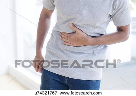 Stock Photo - Man touching his stomach in pain. Fotosearch