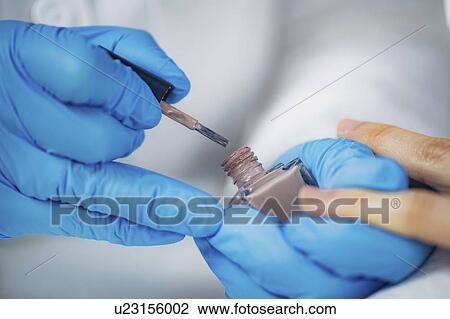 Stock Image - Manicurist painting nails. Fotosearch