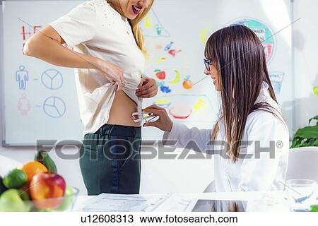 Stock Image - Measuring body fat with callipers. Fotosearch