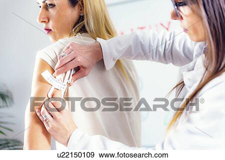 Stock Photo - Measuring body fat with callipers. Fotosearch