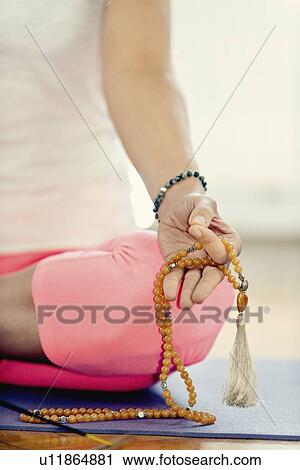 Stock Image - Meditating with rosary beads. Fotosearch