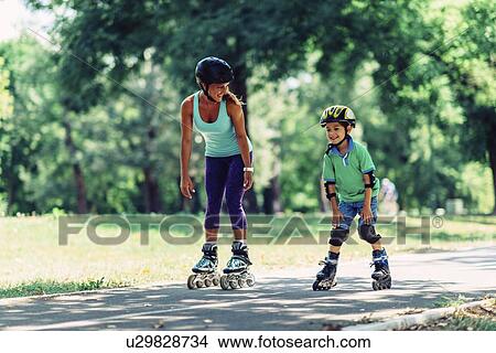 Mother teaching son to roller skate in park View Large Photo Image Picture - Mother teaching son to roller skate in park. Fotosearch