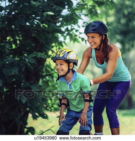 Mother teaching son to roller skate in park View Large Photo Image Stock Image - Mother teaching son to roller skate in park. Fotosearch