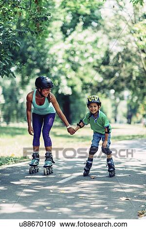 Mother teaching son to roller skate in park View Large Photo Image Stock Photo - Mother teaching son to roller skate in park. Fotosearch