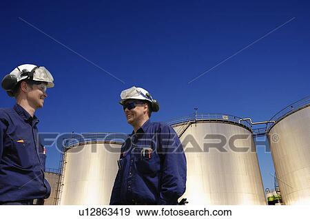 Oil workers and fuel storage tanks View Large Photo Image Stock Photo - Oil workers and fuel storage tanks. Fotosearch