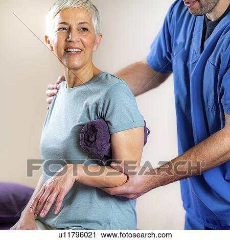 Stock Image - Physical therapist examining patient's arm. Fotosearch