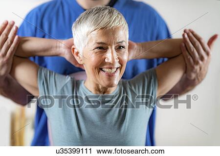 Stock Image - Physical therapist examining patient's arm. Fotosearch