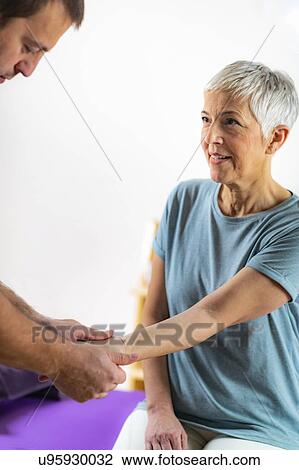 Stock Image - Physical therapist examining patient's wrist. Fotosearch