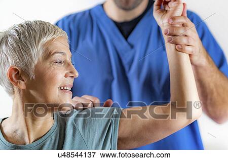 Stock Photo - Physical therapist examining patient's arm. Fotosearch