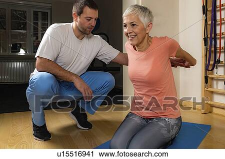 Stock Image - Physical therapist stretching senior woman. Fotosearch
