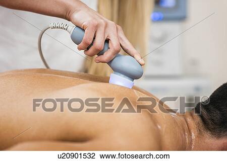 Stock Image - Physiotherapist using ultrasound. Fotosearch