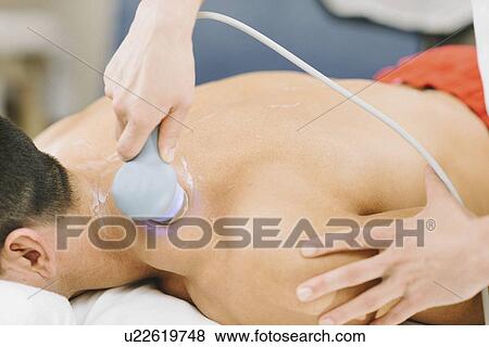 Stock Photo - Physiotherapist using ultrasound. Fotosearch