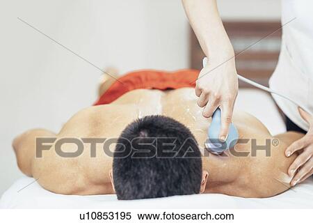 Stock Photography - Physiotherapist using ultrasound. Fotosearch