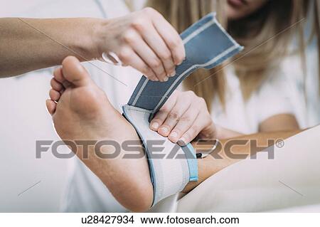 Picture - Placing TENS electrodes on ankle. Fotosearch