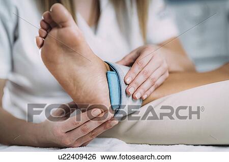 Stock Photograph - Placing TENS electrodes on ankle. Fotosearch