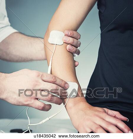Stock Image - Placing TENS electrodes on arm. Fotosearch