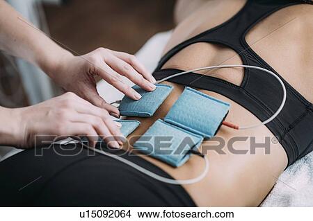 Picture - Placing TENS electrodes on back. Fotosearch